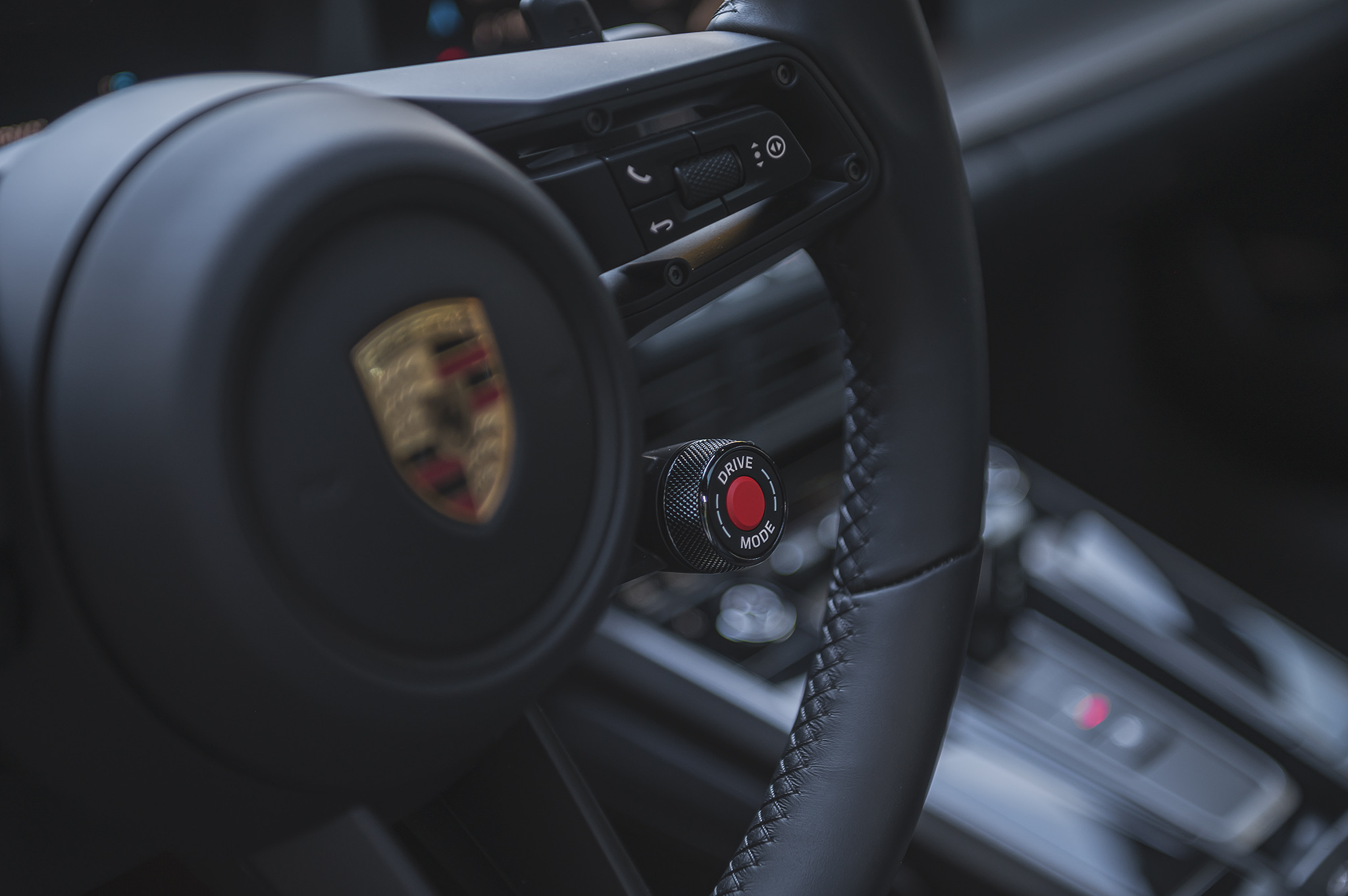 Porsche 911 steering wheel close-up with drive mode selector and premium interior controls