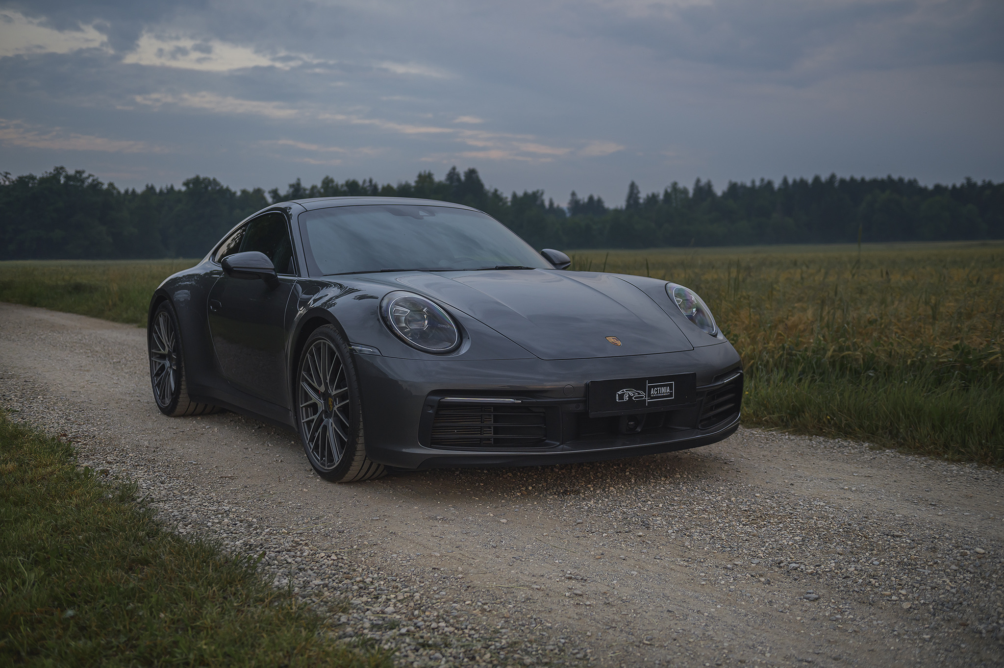 Porsche 911 Carrera 992.2 in graphite grey on a gravel country road – Actinia