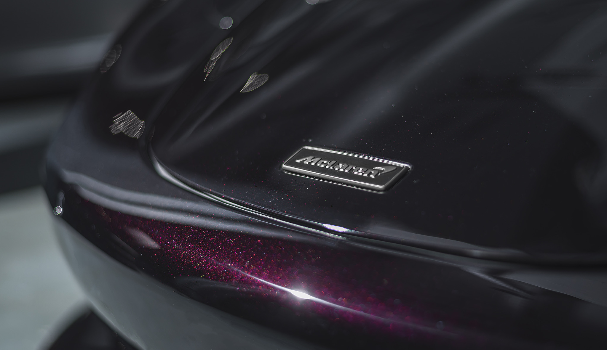 Close-up of McLaren 750S badge on glossy paintwork with metallic reflections 
